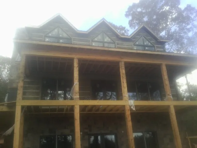 Dormers and porch framing on a large log home under construction — Roof Coating work by our crew in East Hampstead