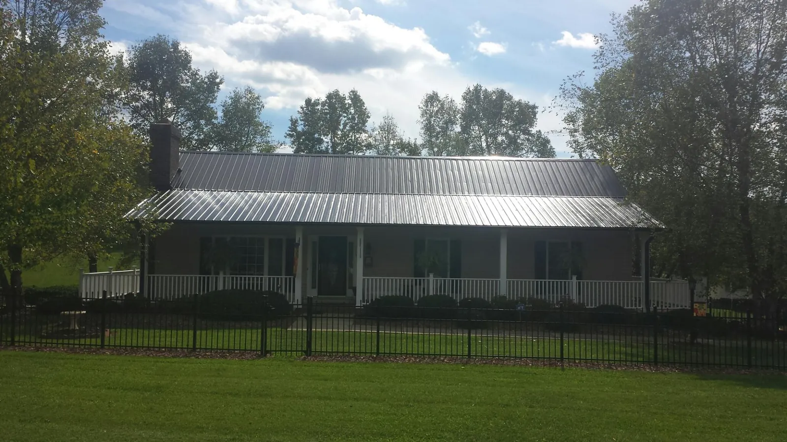 Gray metal roof on a brick ranch with a full width front porch — Gutter Guard Installation work by our crew in East Hampstead