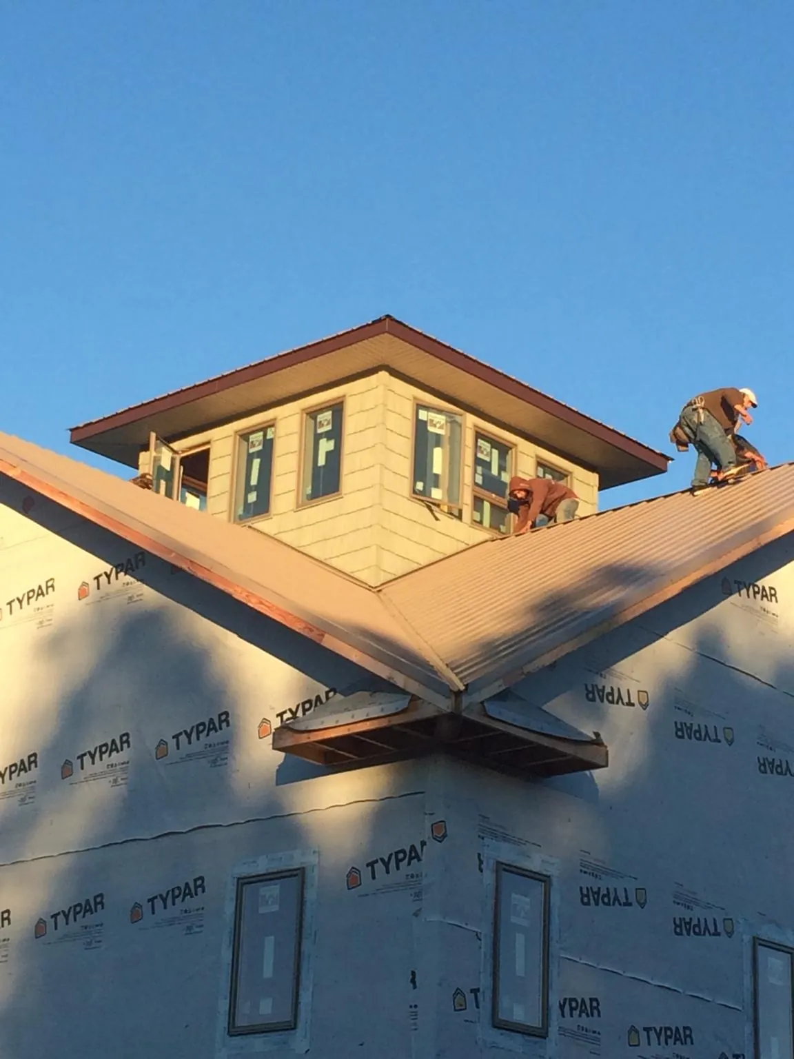 Roofers working around a rooftop cupola on a new metal roof at sunset — Roof Waterproofing in East Hampstead by Roofing Brothers